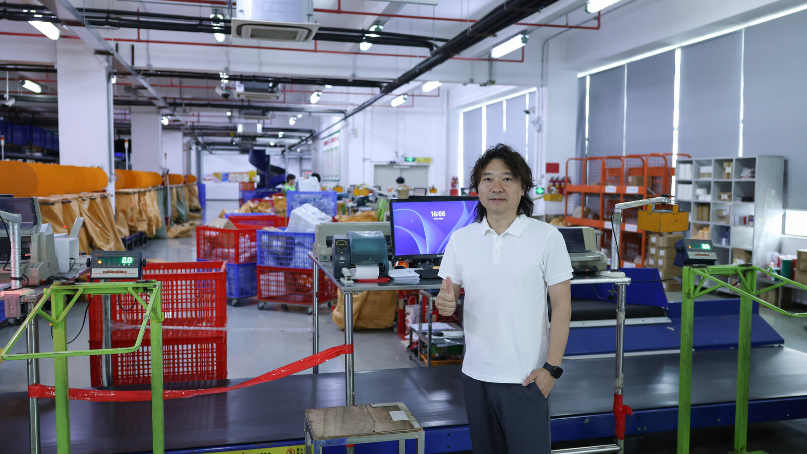 Janson standing at a packing and dispatch station with monitors, label equipment, scales and sorting crates