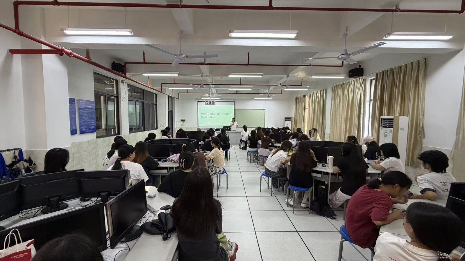 A classroom of people seated at computer workstations during a process training session