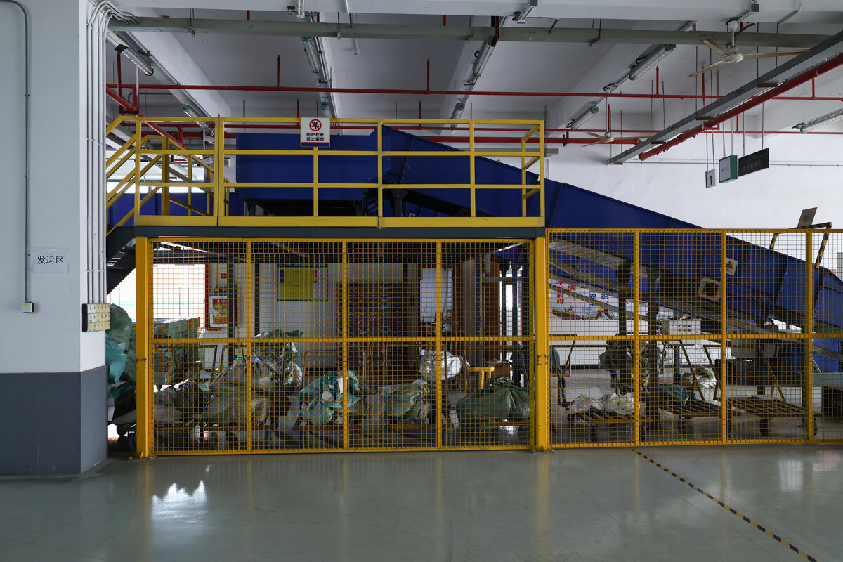 A yellow metal safety cage encloses a separated storage area on the warehouse floor.
