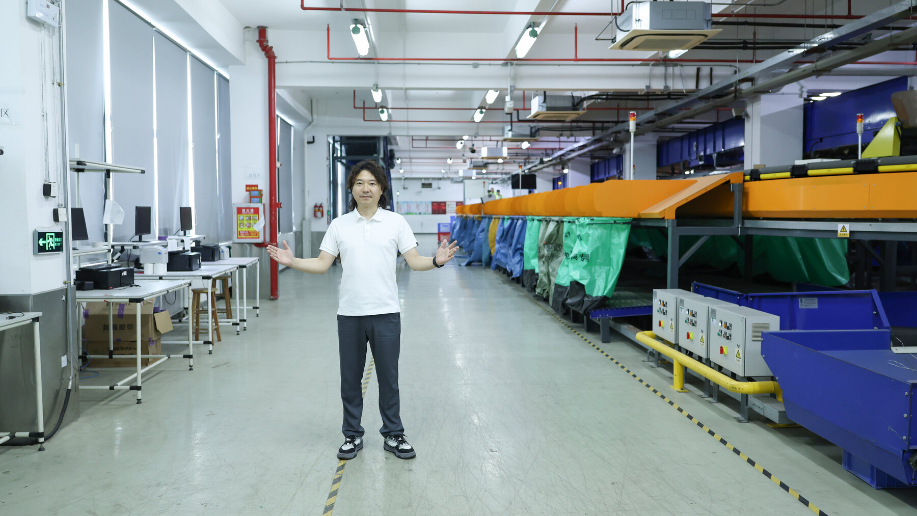 Janson standing beside sorting equipment and processing stations in an ASG warehouse aisle.