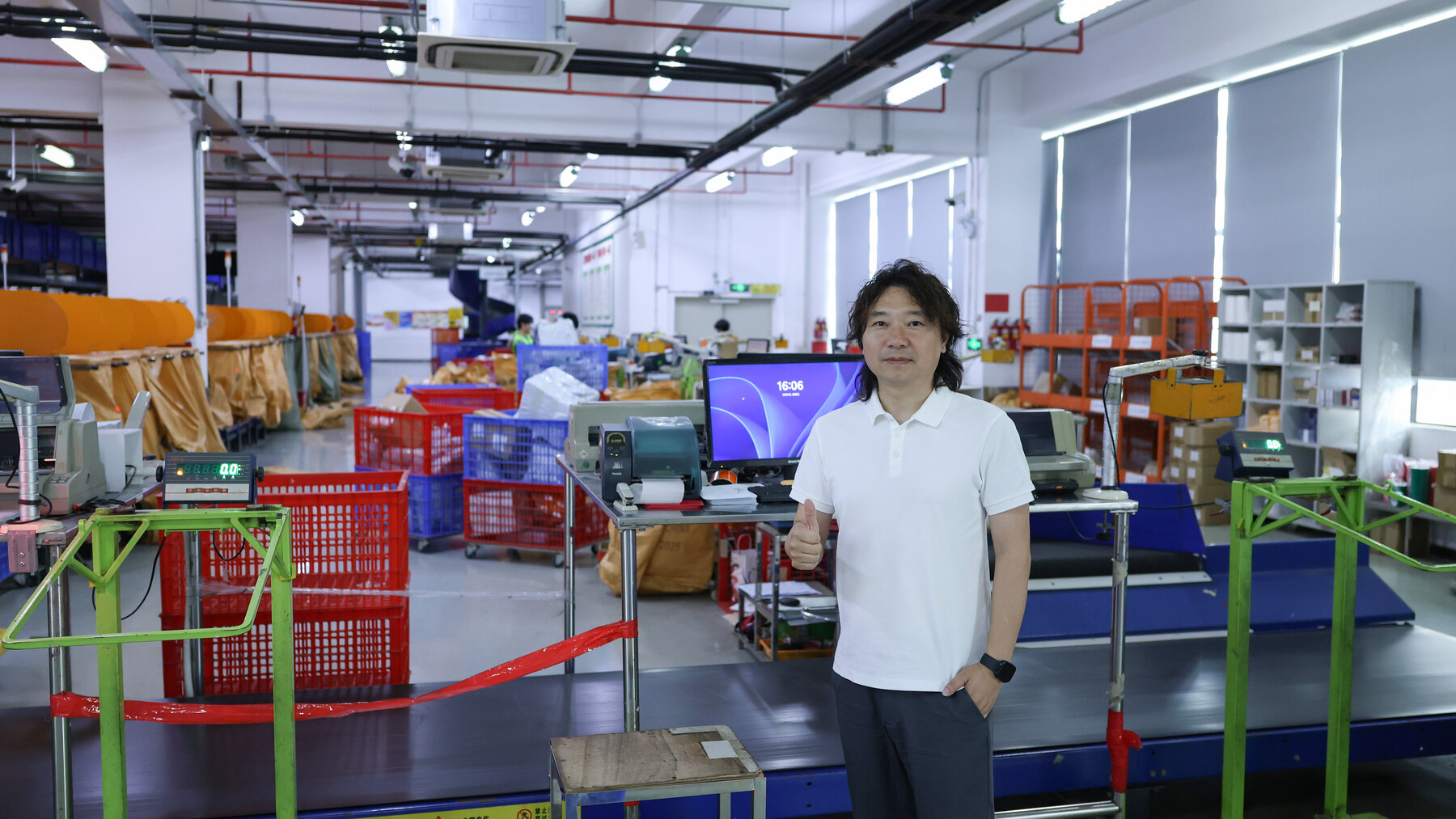 Janson standing beside the control area in an ASG warehouse with conveyors, workstations, and sorting crates behind him.