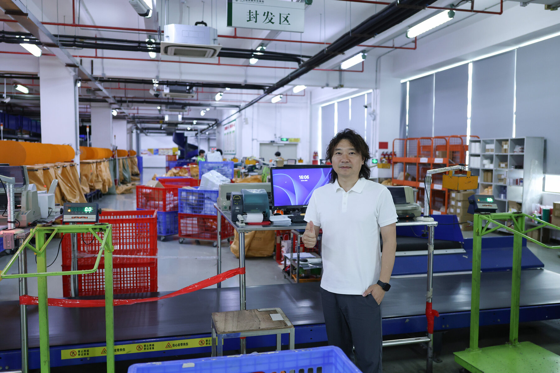 ASG warehouse sorting floor with conveyors, color-coded crates, workstations, and an employee beside the operating area.