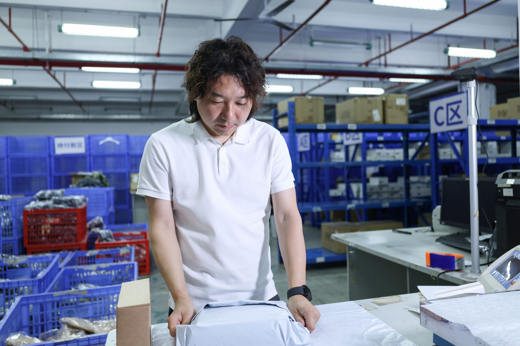Worker handling a parcel at a warehouse workbench.