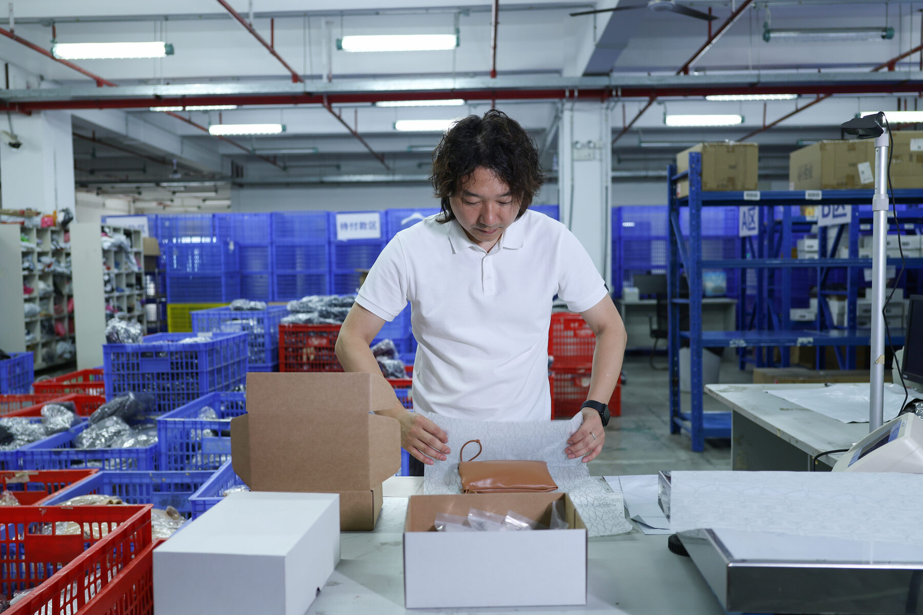 A man arranging protective wrap around an item at a warehouse packing bench.
