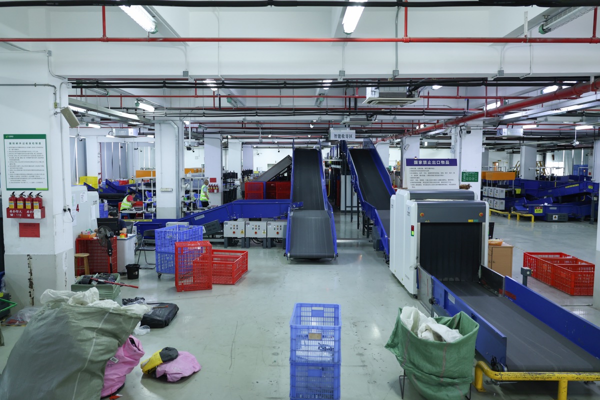 Conveyor belts and red and blue plastic crates in a warehouse sorting area.