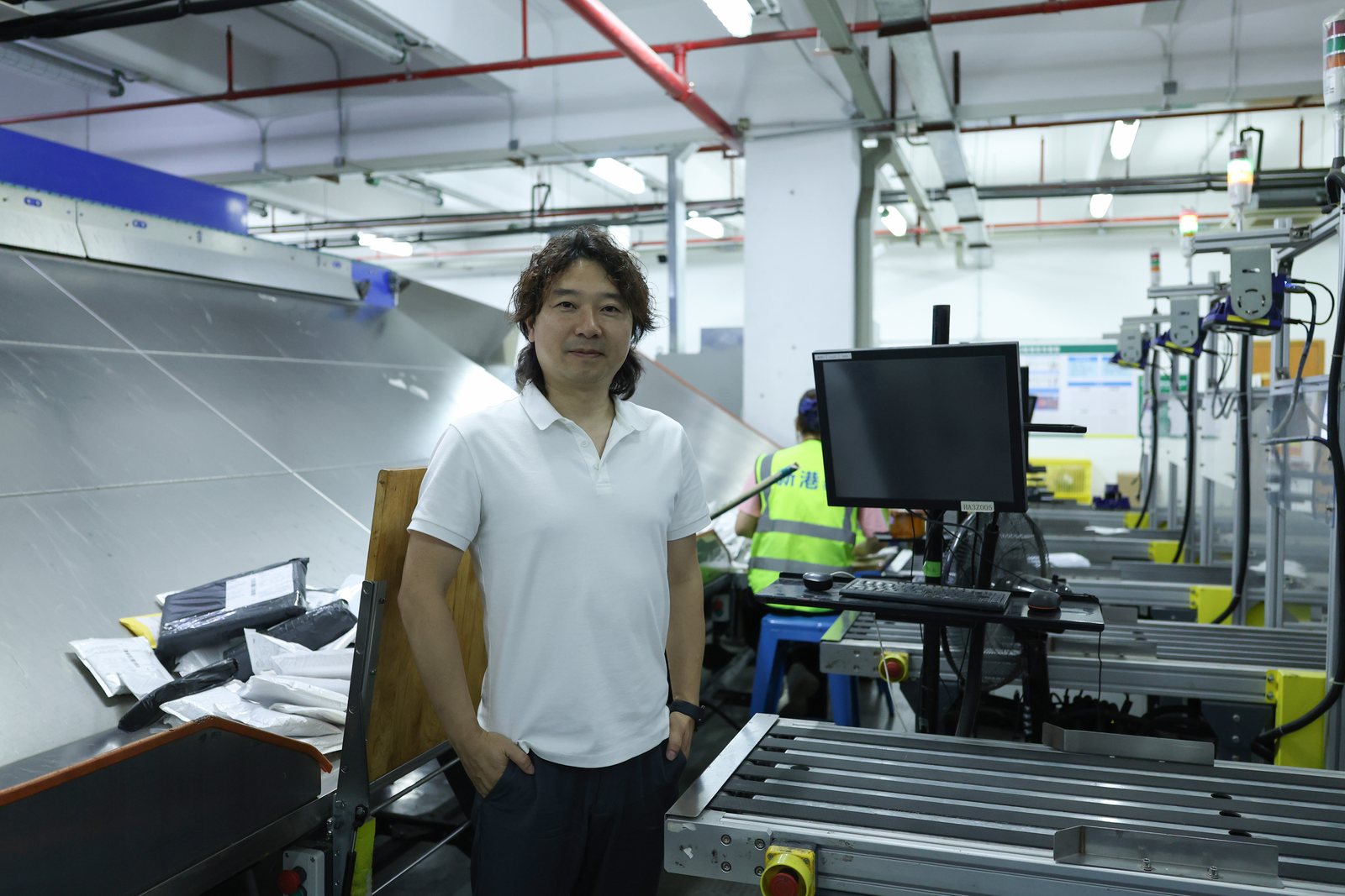 Janson standing beside ASG warehouse sortation equipment, a monitor and packed parcels.